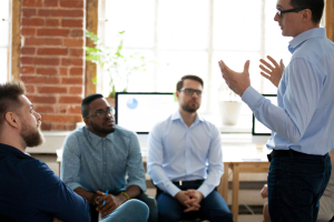 Confident male coach speaking at diverse team meeting