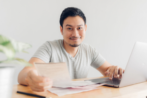 Man with laptop looking at paperwork