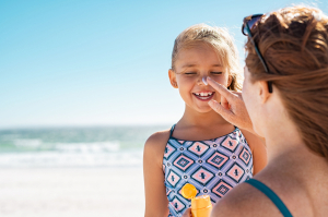 Mother applying sunscreen to her daughter at the beach