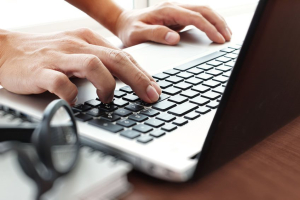 Close up business man hand working on blank screen laptop computer on wooden desk as concept