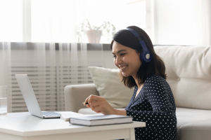 Smiling young woman watching a webinar with headphones on
