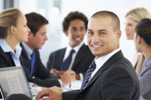 Portrait of male executive with office meeting in background Portrait of male executive with office meeting in background