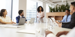 Businesswoman standing giving presentation to colleagues in modern open plan office.