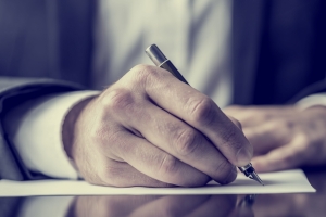 Close up of a man's hands signing a document