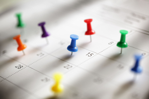 Closeup of calendar with thumb tacks on various dates