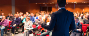 Business man presenting to an auditorium full of people