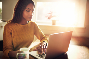 Woman using a laptop in a sunny kitchen