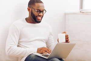 Man using a laptop and drinking coffee