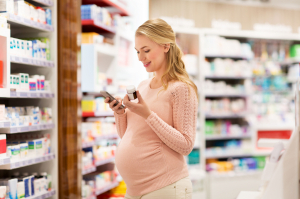 Pregnant woman using a mobile app while reviewing over the counter medicine