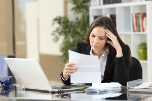 Worried businesswoman reading a notification sitting in a desktop at office Worried businesswoman reading a notification sitting in a desktop at office