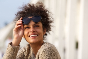 Close up portrait of a happy smiling young woman outside with sunglasses