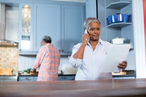 Senior woman on the phone in her kitchen reading a document