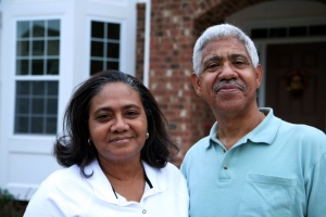 Elderly couple standing in front of their home