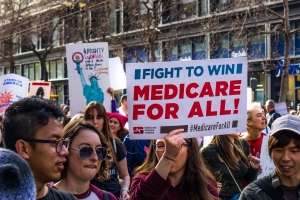 Participant to the Women's March event holds "Medicare for all" sign while marching on Market street in downtown San Francisco