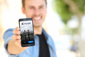 Man holding a mobile phone displaying the Flex mobile app