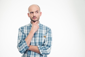 Attractive thoughtful young man in plaid shirt looking away over white background